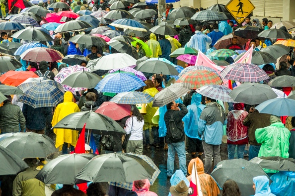 Quito, Ecuador - August 27, 2015: Large crowd and many umbrellas in city streets during demonstrations